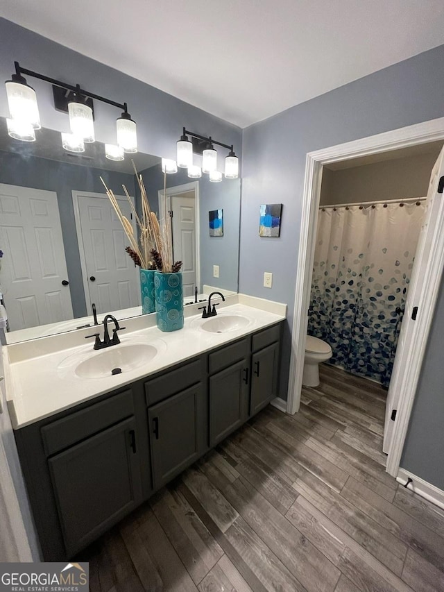 full bath featuring toilet, a sink, and wood finished floors