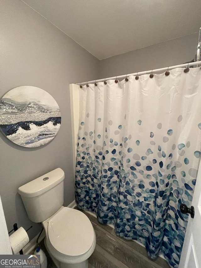 bathroom featuring toilet, wood finished floors, and a shower with shower curtain