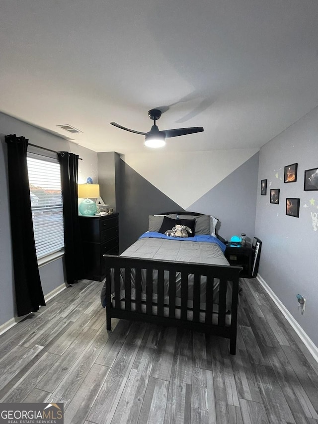 bedroom featuring visible vents, a ceiling fan, baseboards, and wood finished floors