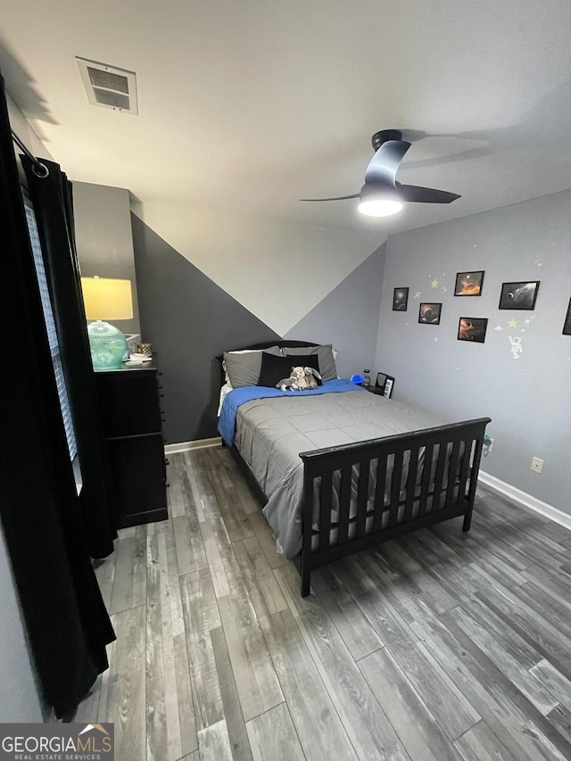bedroom featuring a ceiling fan, visible vents, vaulted ceiling, baseboards, and light wood-style flooring