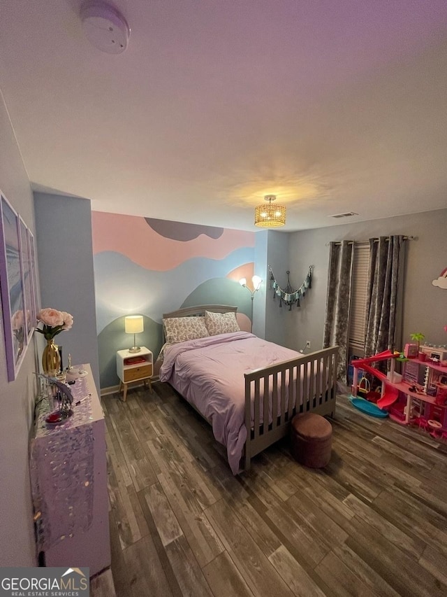 bedroom with a notable chandelier, wood finished floors, and visible vents