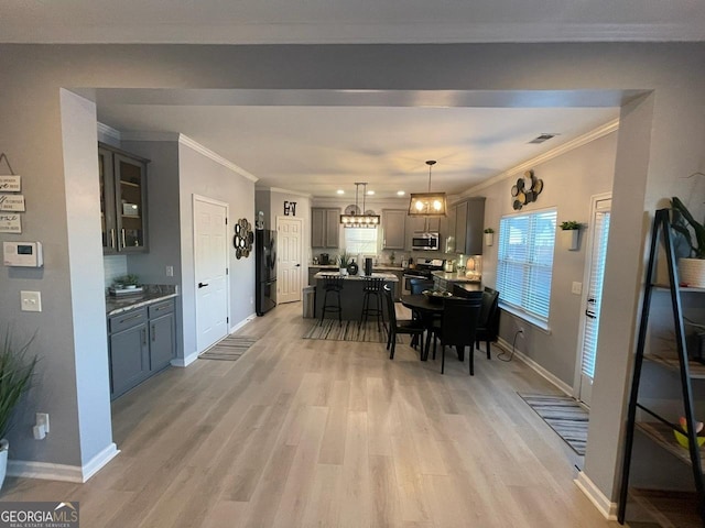 dining area with baseboards, ornamental molding, light wood-type flooring, and a wealth of natural light