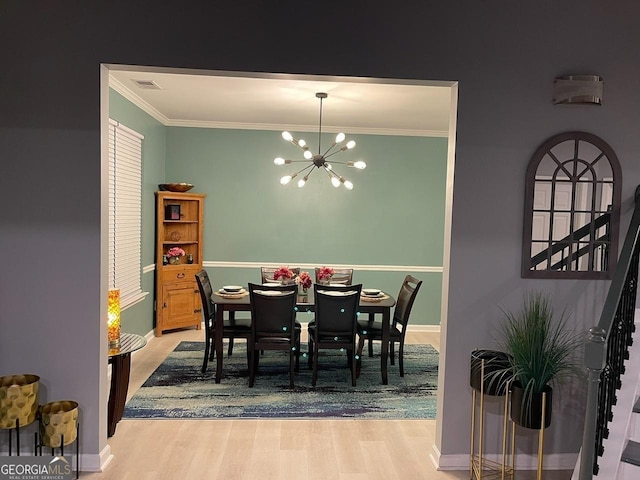 dining room featuring a chandelier, ornamental molding, wood finished floors, and visible vents