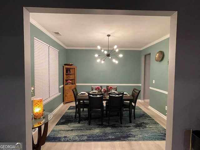 dining area with crown molding, wood finished floors, and a notable chandelier