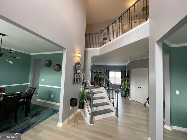 staircase featuring crown molding, baseboards, and wood finished floors