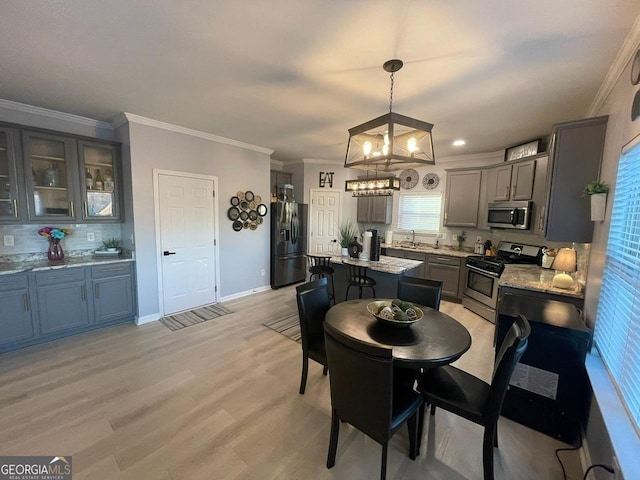 kitchen featuring a notable chandelier, a sink, stainless steel appliances, decorative backsplash, and a kitchen island