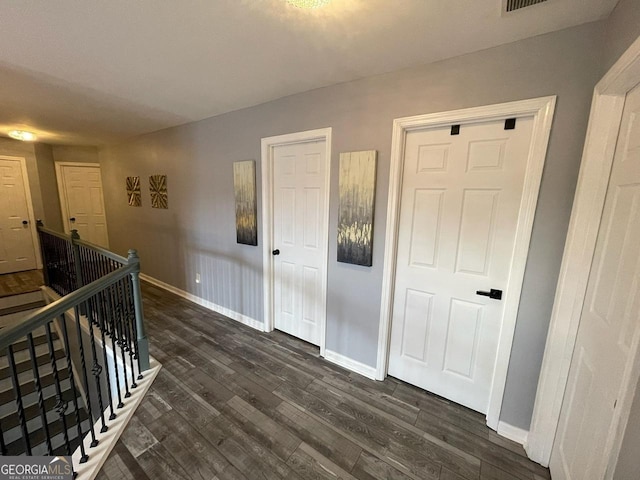 corridor with baseboards, dark wood-type flooring, and an upstairs landing