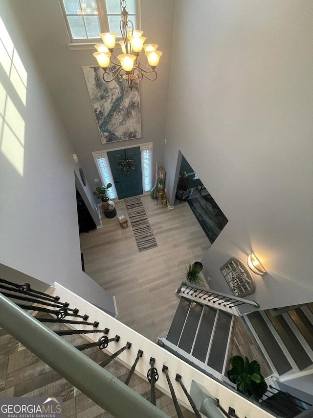 foyer entrance with a high ceiling, an inviting chandelier, and wood finished floors