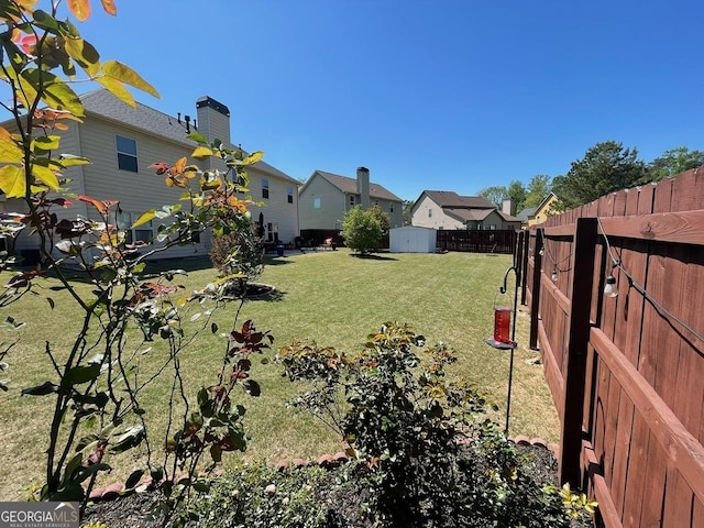 view of yard featuring a storage shed, fence, and an outdoor structure