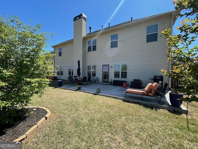 rear view of house with a lawn, a chimney, and a patio area