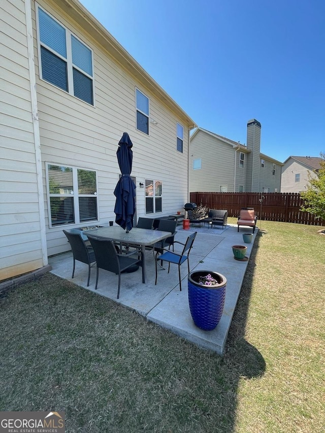 rear view of property featuring a patio area, fence, and a yard
