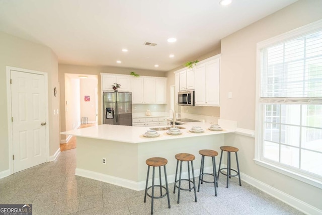 3819 Meandering Way SW, Lilburn, GA 30047 - kitchen with stainless steel appliances, a peninsula, visible vents, baseboards, and a breakfast bar