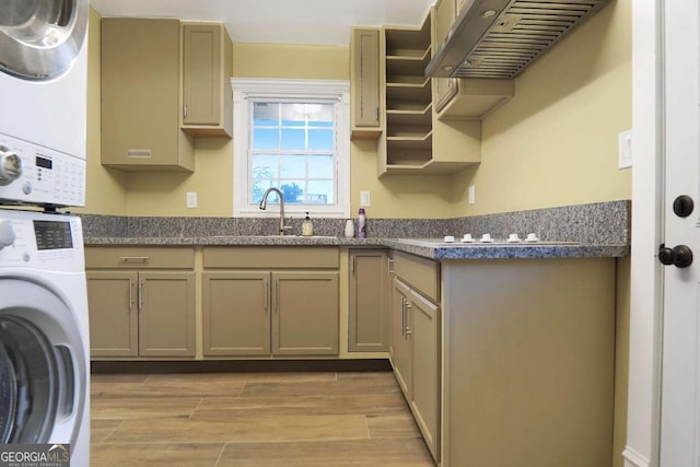 laundry room with cabinet space, light wood finished floors, stacked washer / dryer, and a sink