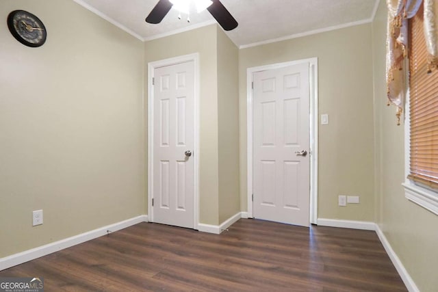 unfurnished bedroom featuring dark wood-type flooring, crown molding, baseboards, and ceiling fan