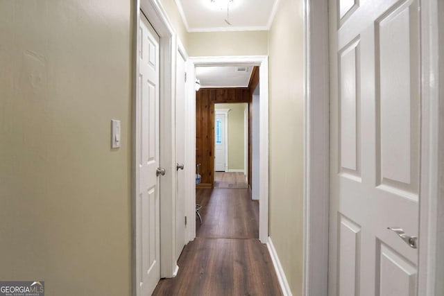 corridor featuring dark wood-type flooring, crown molding, baseboards, and attic access