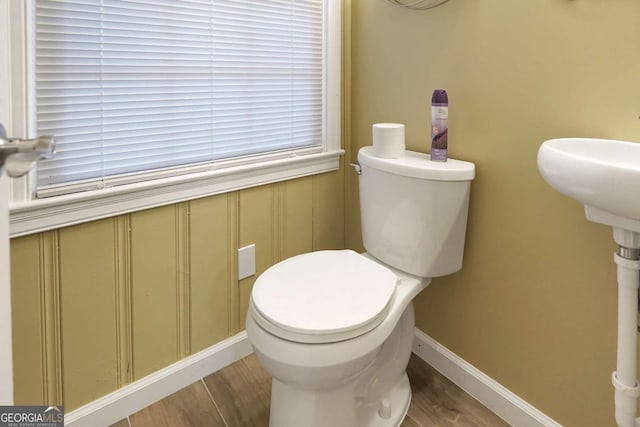 bathroom featuring toilet, wood finished floors, and baseboards