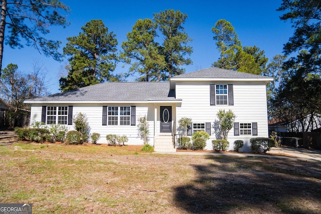 split level home with fence, a front lawn, and roof with shingles