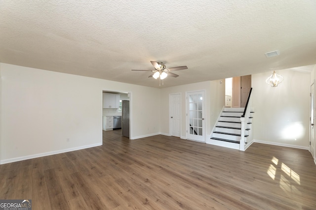 unfurnished living room featuring visible vents, baseboards, wood finished floors, and stairs