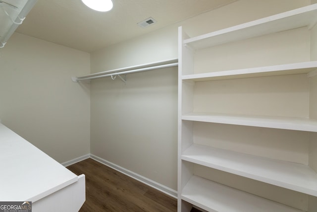 walk in closet with dark wood-style flooring and visible vents