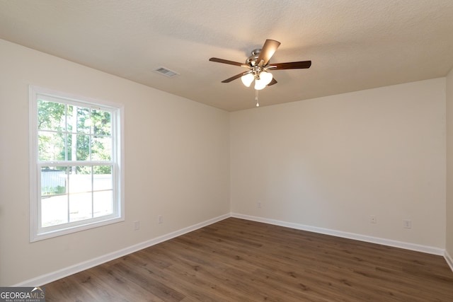 spare room featuring dark wood finished floors, baseboards, a ceiling fan, and visible vents