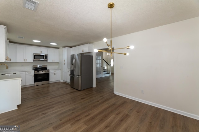 kitchen featuring a sink, dark wood finished floors, baseboards, an inviting chandelier, and appliances with stainless steel finishes
