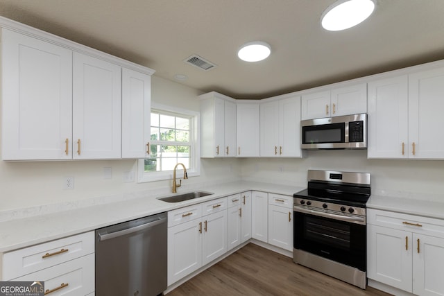 kitchen with a sink, visible vents, white cabinetry, light countertops, and appliances with stainless steel finishes