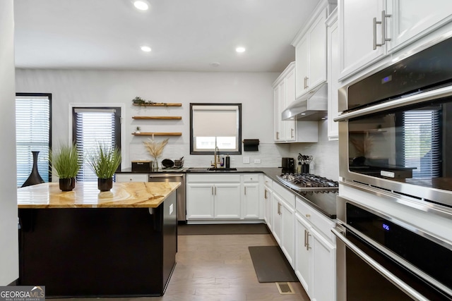 371 Northaven Ave, Suwanee, GA 30024 - kitchen featuring under cabinet range hood, decorative backsplash, white cabinetry, recessed lighting, and dark wood-type flooring