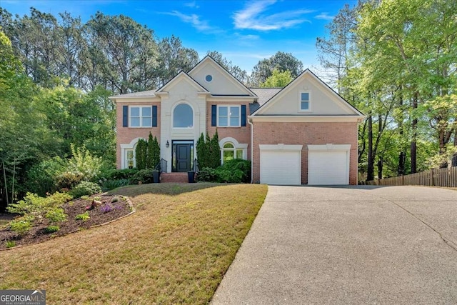 colonial house featuring brick siding, a front lawn, driveway, and fence