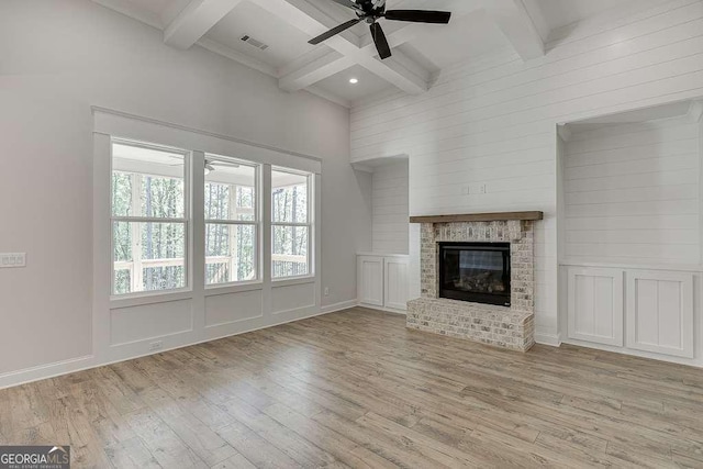 unfurnished living room with wood finished floors, beamed ceiling, a ceiling fan, coffered ceiling, and a fireplace