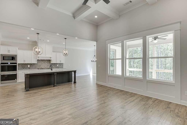 living area featuring a ceiling fan, beamed ceiling, light wood-type flooring, crown molding, and a chandelier