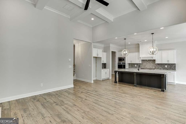 kitchen with oven, stainless steel microwave, beam ceiling, decorative backsplash, and light countertops