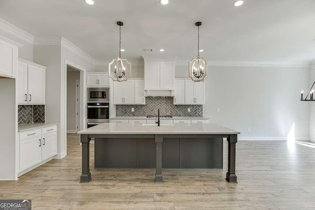 kitchen with a chandelier, stainless steel appliances, white cabinets, backsplash, and a breakfast bar area
