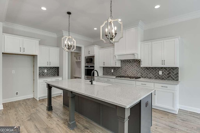 kitchen featuring a chandelier, a sink, stainless steel appliances, white cabinets, and ornamental molding