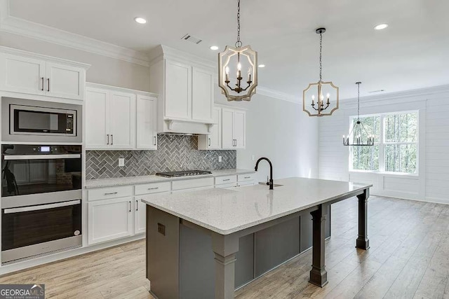 kitchen with a chandelier, appliances with stainless steel finishes, white cabinetry, ornamental molding, and decorative backsplash