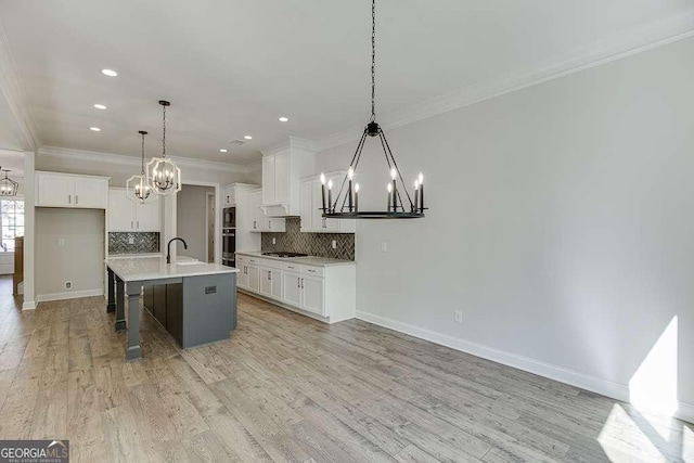 kitchen with a chandelier, stovetop, baseboards, crown molding, and backsplash