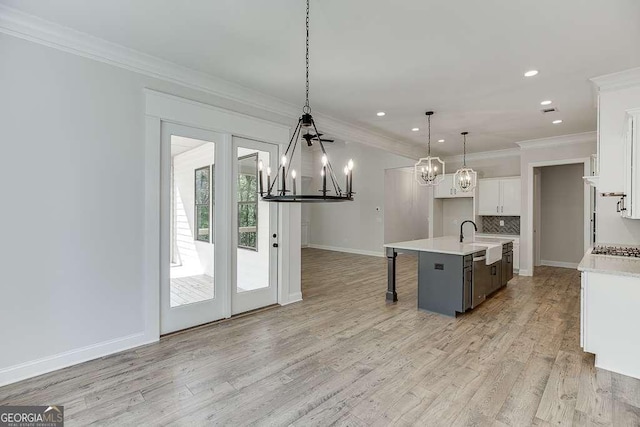 kitchen featuring a chandelier, a sink, light countertops, decorative backsplash, and crown molding