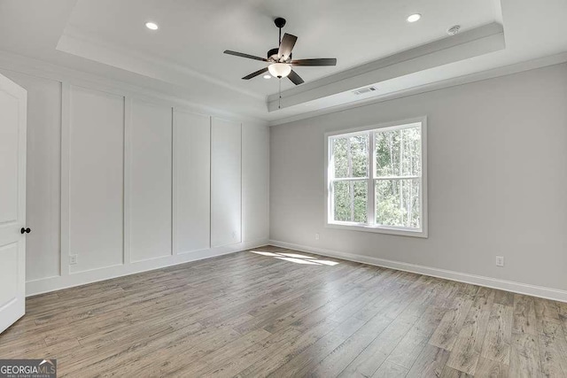 unfurnished room with a tray ceiling, wood finished floors, a ceiling fan, recessed lighting, and baseboards