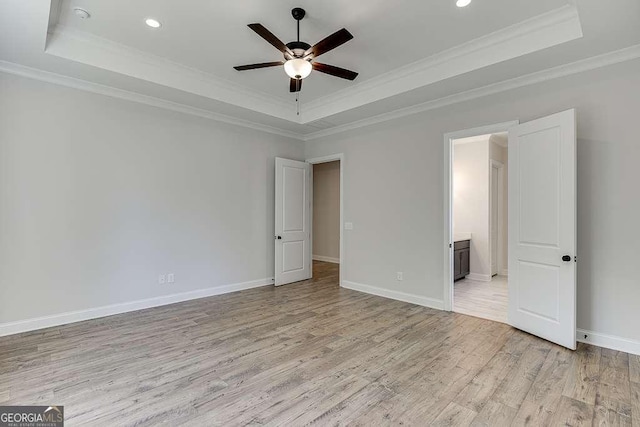 unfurnished bedroom featuring a raised ceiling, light wood finished floors, crown molding, recessed lighting, and baseboards
