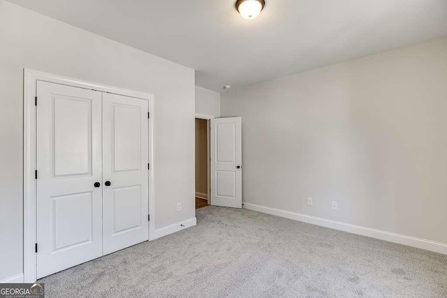 unfurnished bedroom with carpet, a closet, and baseboards