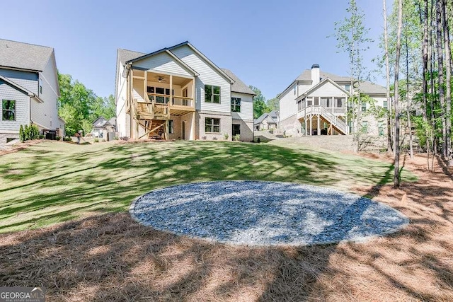 rear view of house featuring ceiling fan, stairway, a yard, and a residential view
