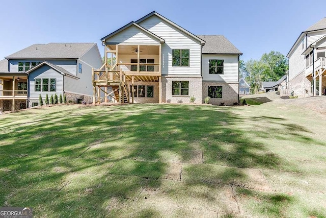back of property with ceiling fan, stairway, a lawn, and brick siding
