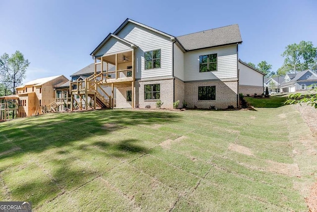 back of house featuring a ceiling fan, stairway, a lawn, brick siding, and a deck