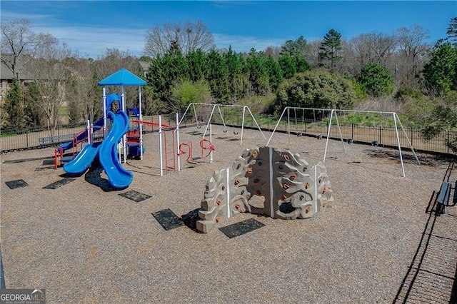 community play area featuring fence and view of scattered trees