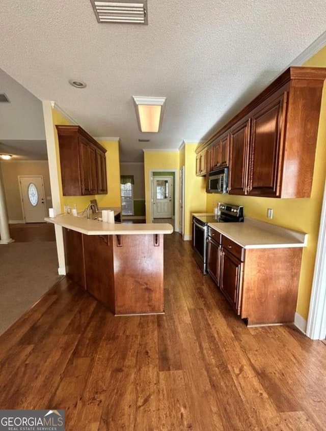 kitchen with light countertops, visible vents, a peninsula, a kitchen bar, and appliances with stainless steel finishes