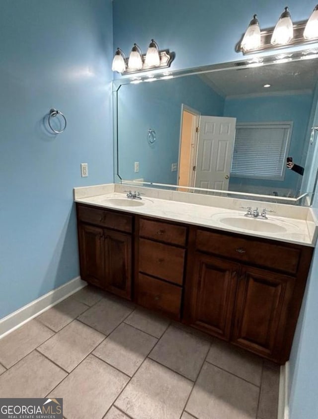bathroom with double vanity, tile patterned flooring, baseboards, and a sink