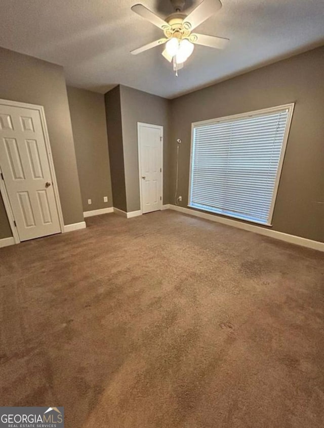 unfurnished bedroom with ceiling fan, baseboards, and carpet floors