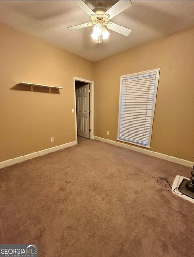 unfurnished room with carpet floors, a ceiling fan, and baseboards