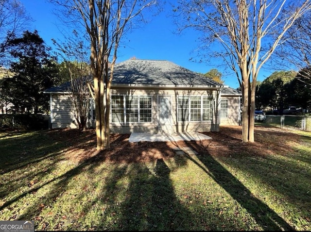 rear view of property featuring fence, a yard, and a patio