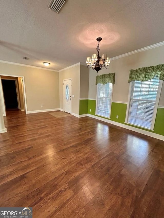 interior space featuring wood finished floors, a textured ceiling, an inviting chandelier, ornamental molding, and visible vents