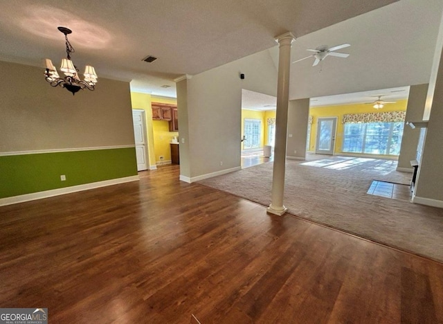 unfurnished living room with dark wood-style floors, ceiling fan with notable chandelier, baseboards, visible vents, and ornate columns